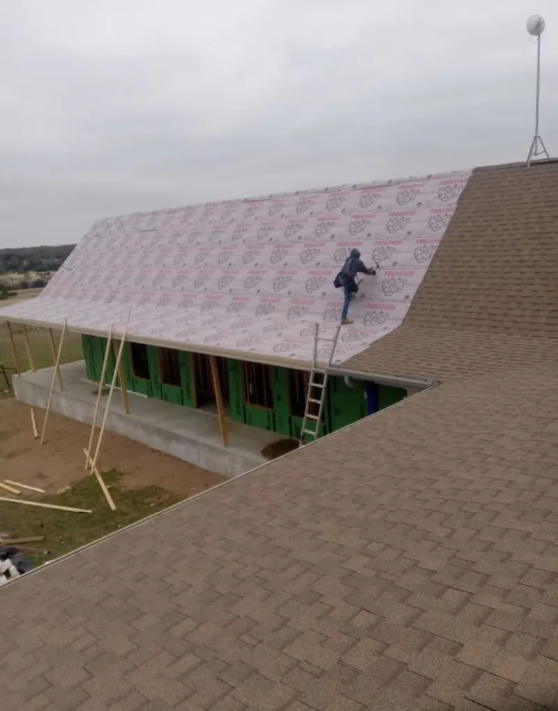 Worker preparing underlayment for a metal roof installation in Warrensville Heights